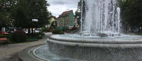 Una fuente circular con varios chorros de agua en una plaza pública.
