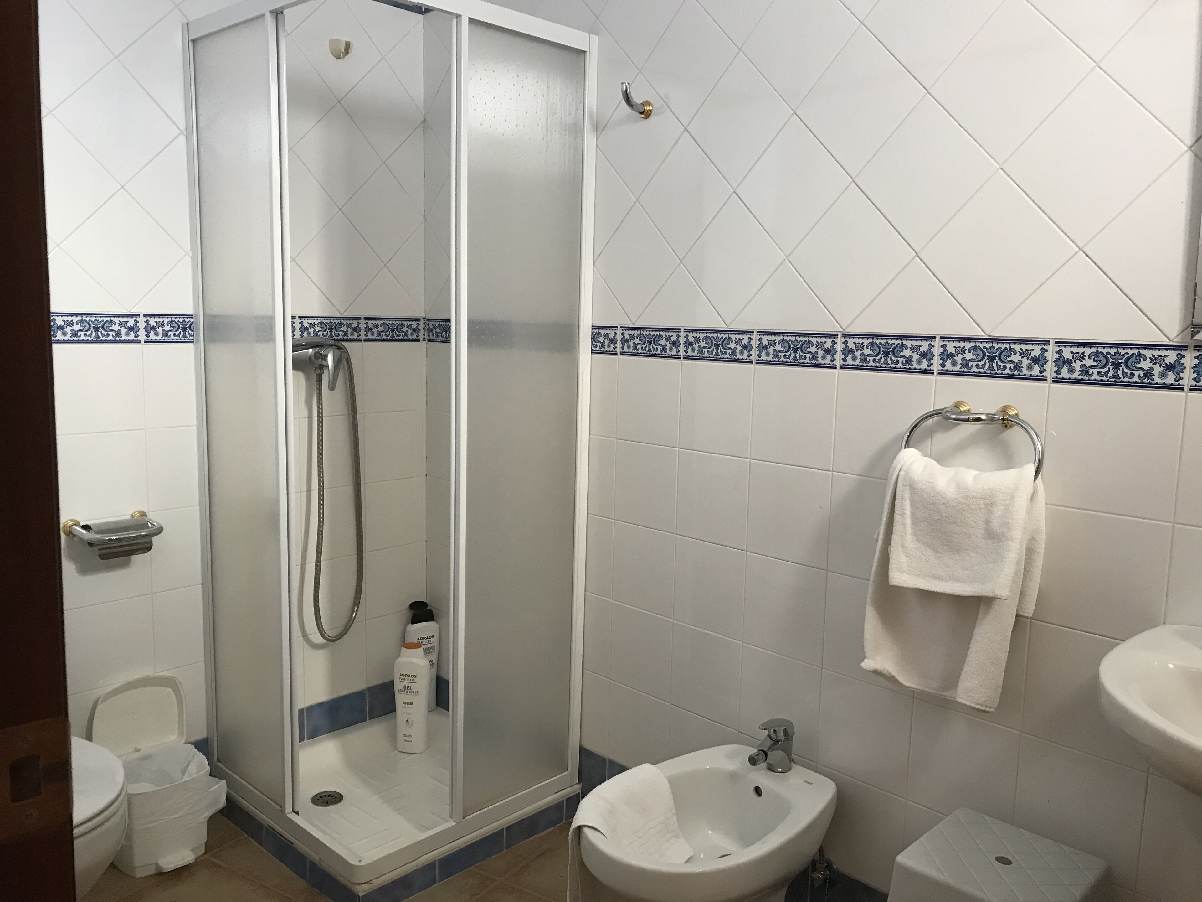 Un baño con ducha de vidrio, un bidé, un lavabo y un inodoro.