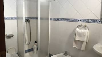 Un baño con ducha de vidrio, un bidé, un lavabo y un inodoro.