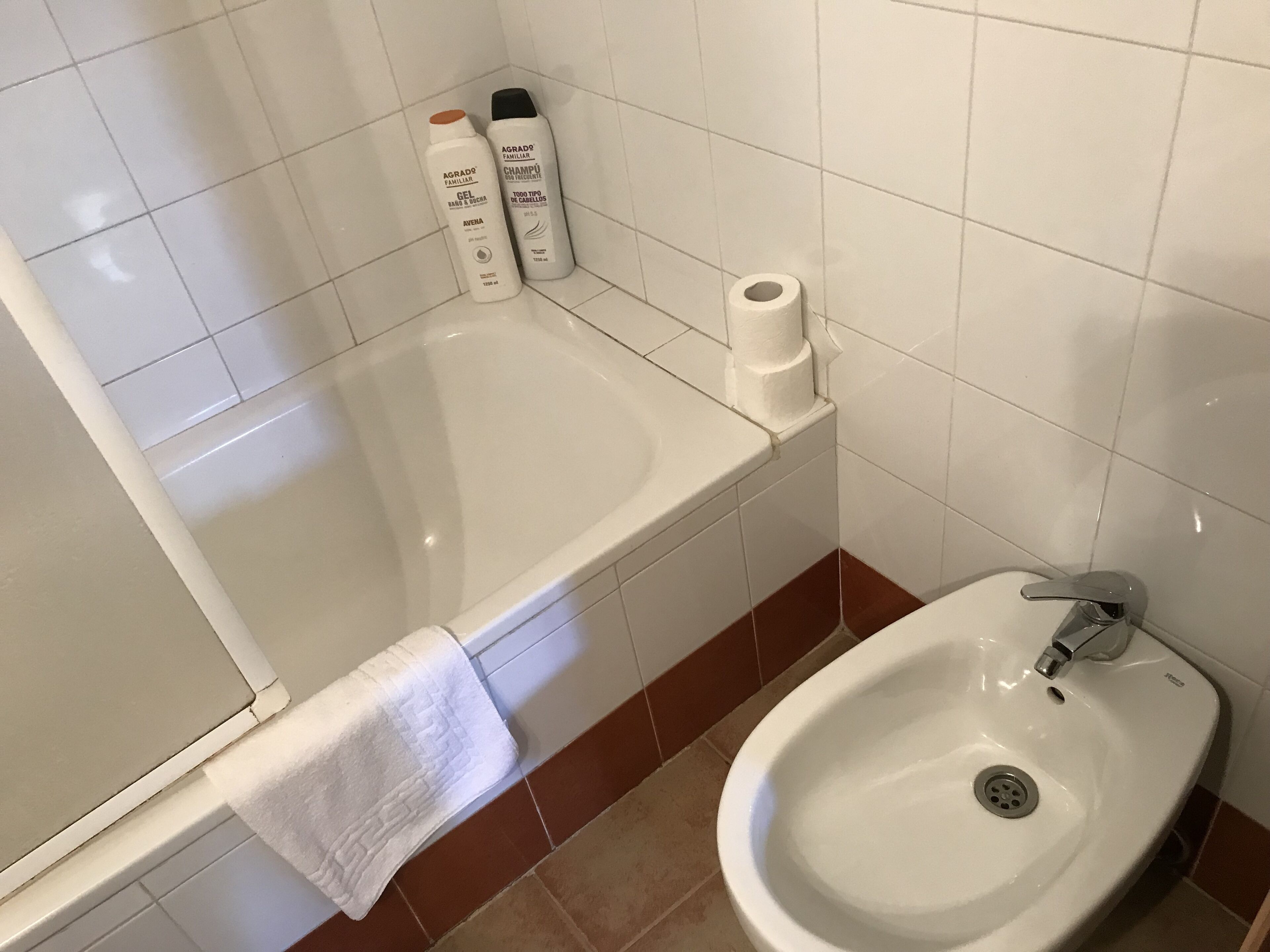 Un baño con bañera, lavamanos y artículos de aseo en la pared.