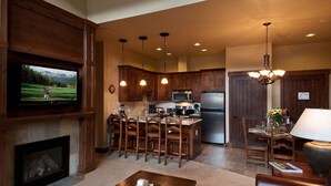 Una cocina moderna con armarios de madera, una isla central y una zona de comedor con taburetes de bar.