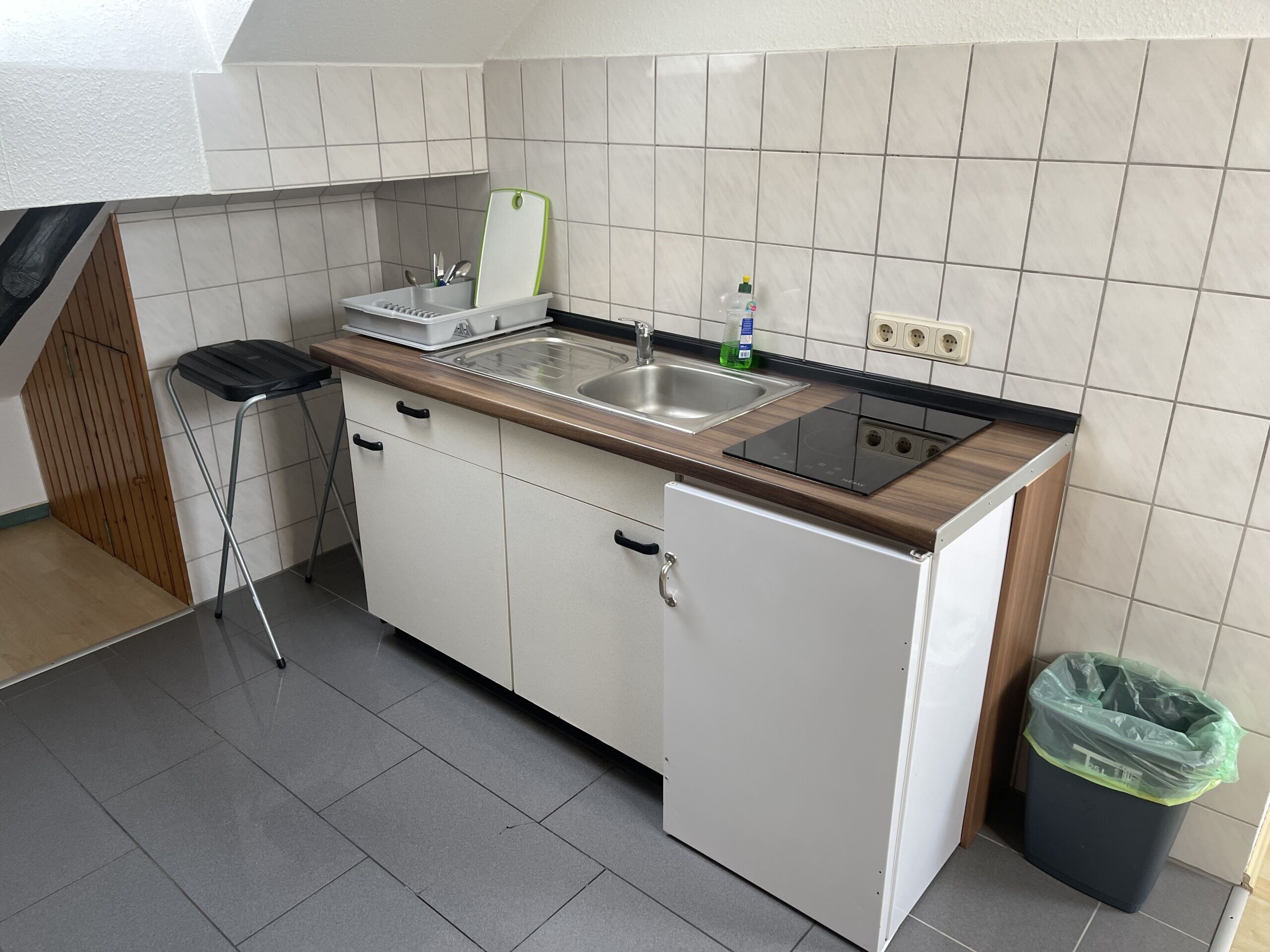 Eine kleine Küche mit Spüle, Arbeitsplatte und einem kleinen Kühlschrank.
