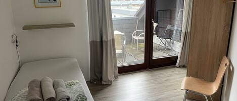 Une chambre d’hôtel avec un lit, une chaise, une armoire en bois, un balcon avec vue et un tableau au mur.
