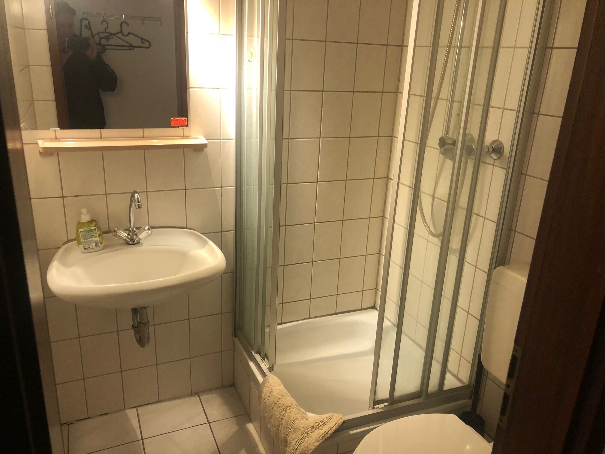A bathroom with a sink, mirror, and glass shower enclosure.