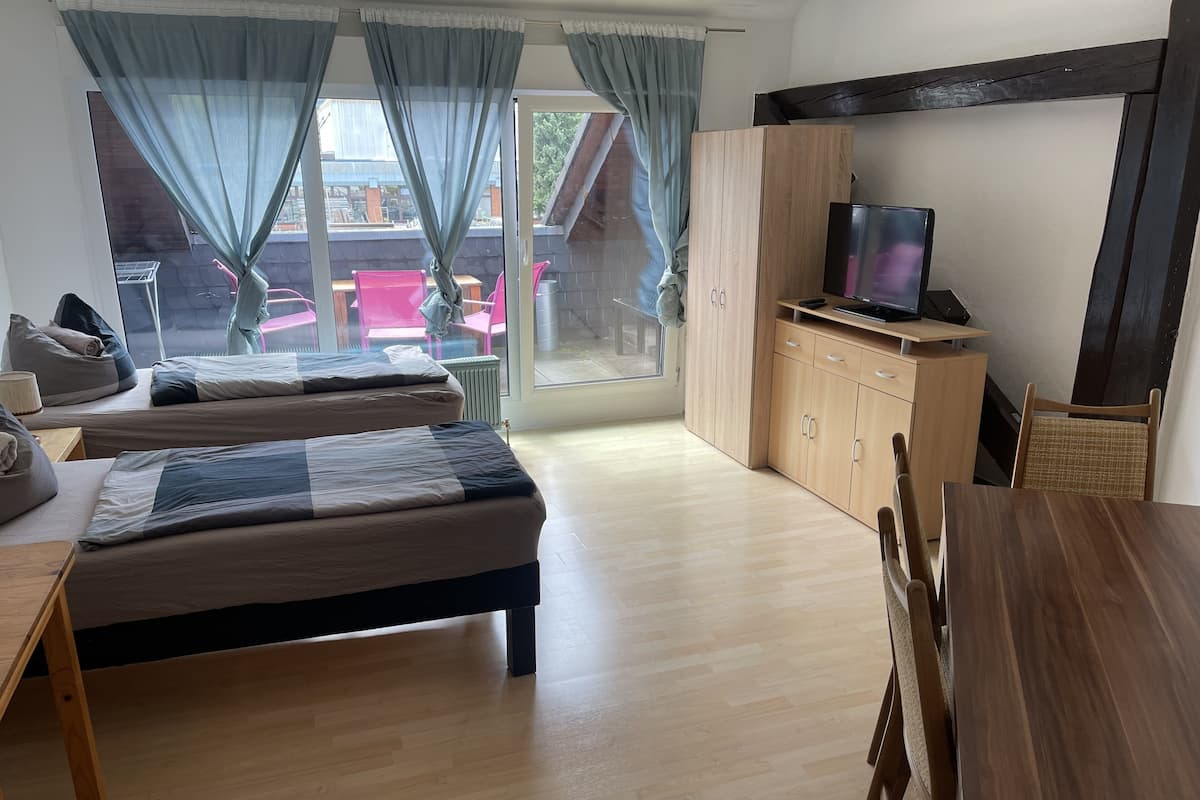 Una habitación con dos camas, una mesa de madera, un televisor y vistas al exterior.