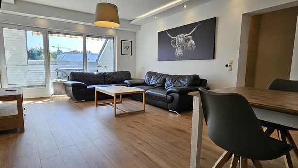 A modern living room with a sofa, a coffee table, and a dining table. - Bed4you Gästehaus 1 (Fuldabruck)
