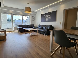 A modern living room with a sofa, a coffee table, and a dining table.