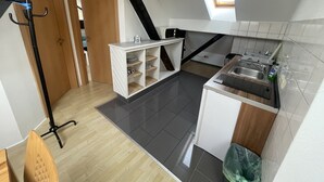 A compact kitchen with a black staircase, a small window, and a white tiled backsplash. - Bed4you Gästehaus 1 (Fuldabruck)