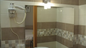 Une salle de bain avec un grand miroir, un sèche-cheveux et un lavabo.