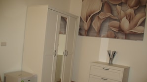 Une pièce avec une armoire blanche, un petit meuble blanc et un papier peint à motifs floraux.