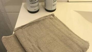 Two bottles of hand soap and a folded towel on a white surface.