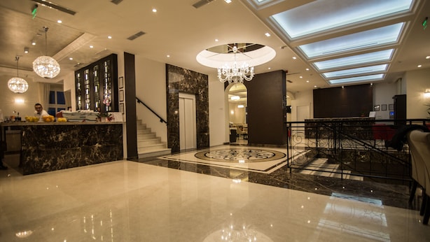 A spacious lobby with a marble floor, a grand chandelier, and a staircase leading to upper floors. - Hotel Central Park (Trebinje)