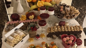A table with various food items, including fruits, desserts, and snacks. - Hotel Central Park (Trebinje)
