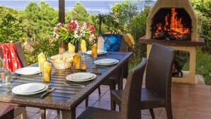 An outdoor dining area with a table set for two, a fire pit, and a view of the ocean. - Solenzara Garden Bungalow Retreat (Solenzara)