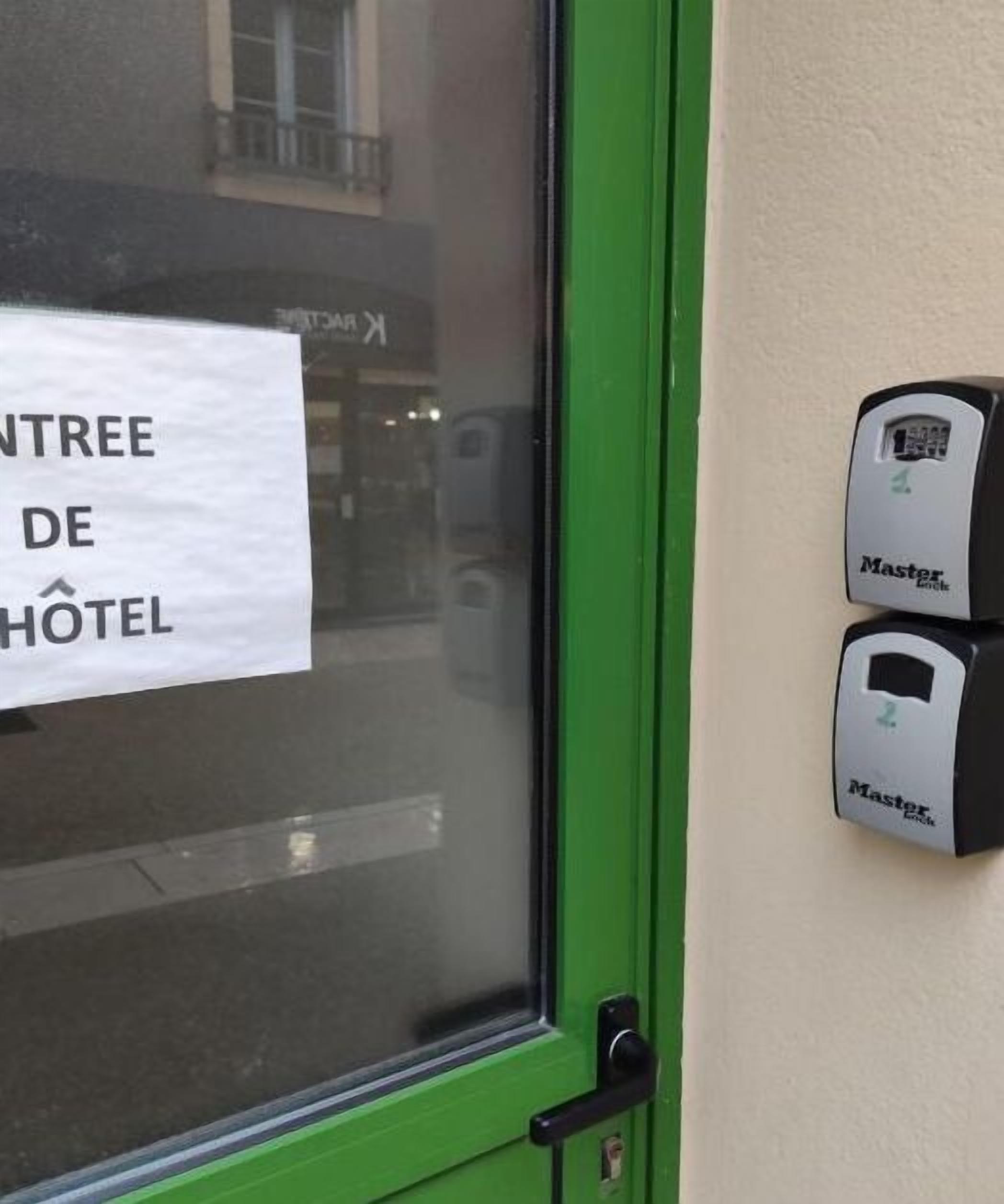 Entrada de hotel con un cartel que dice "ENTREE DE HOTEL" y una puerta con marco verde. Hay dos cerraduras Master en la puerta.
