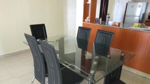 A dining area with a glass table and four black chairs with metal legs. - Memo's Homestay (Mlolongo)