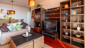 Una sala de estar moderna con un sofá, televisor y una estantería de madera.