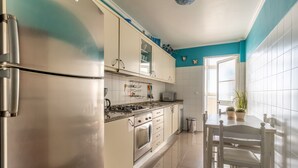 Una cocina moderna con electrodomésticos de acero inoxidable, armarios blancos y una pared de acento color turquesa.