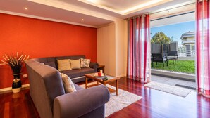 A modern living room with a grey sofa, a wooden coffee table, and a red accent wall. - Casa Branca II (Funchal)