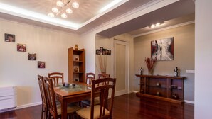 A dining area with a wooden table and chairs, a bookshelf, and wall art. - Casa Branca II (Funchal)
