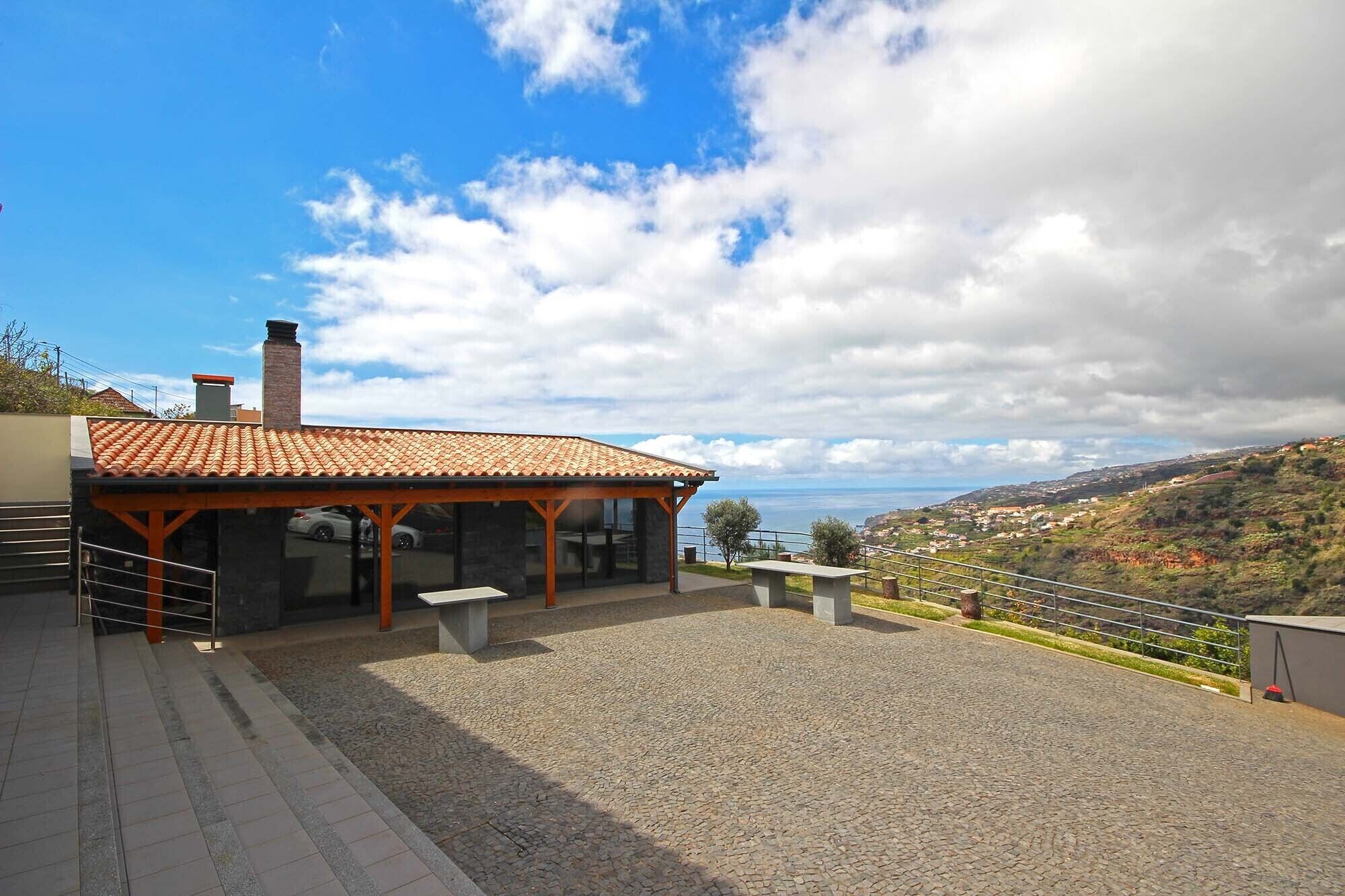 Un edificio con techo de tejas, fachada de piedra y vista al mar.
