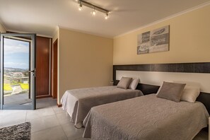 A hotel room with two beds, a large window, and a view of the city. - Gran Horizonte House (Ribeira Brava)
