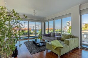 A modern living room with large windows, a grey sofa, a green armchair, and a black coffee table. - Monumental Residence (Funchal)
