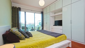 A bedroom with a bed, a TV, and a large window. - Monumental Residence (Funchal)