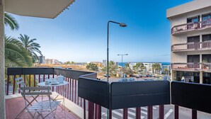 Ein Balkon mit Tisch und Stühlen, mit Blick auf eine Straße und Gebäude.