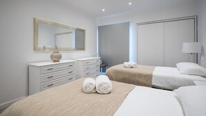 Ein modernes Hotelzimmer mit zwei Betten, einem großen Spiegel, einem Schminktisch und einem Nachttisch.