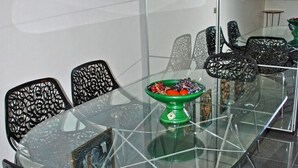 Un espace repas moderne avec une table en verre entourée de chaises noires ornées de motifs complexes.