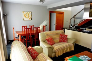A living room with a sofa, chairs, a dining table, and a kitchen area with a counter and cabinets. - Beach Apartment Marfolin 26 El Cotillo (La Oliva)