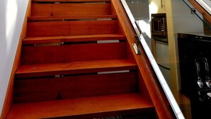 A staircase with wooden steps and glass railings, leading to an upper floor.