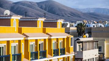 Una hilera de edificios amarillos con numerosas ventanas y balcones, frente a un telón de fondo montañoso.