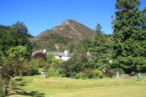 A mountainous landscape with a white building surrounded by lush greenery and trees.