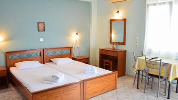 A hotel room with a double bed, a desk with a chair, a mirror, and a window with curtains.