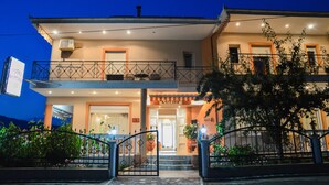A two-story hotel with a balcony, a sign indicating it is a hotel, and a well-lit entrance. - Vergina (Thasos)