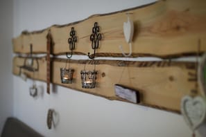 A wooden wall-mounted rack with hooks and candle holders. - Hotel am Kellhof (Hilzingen)