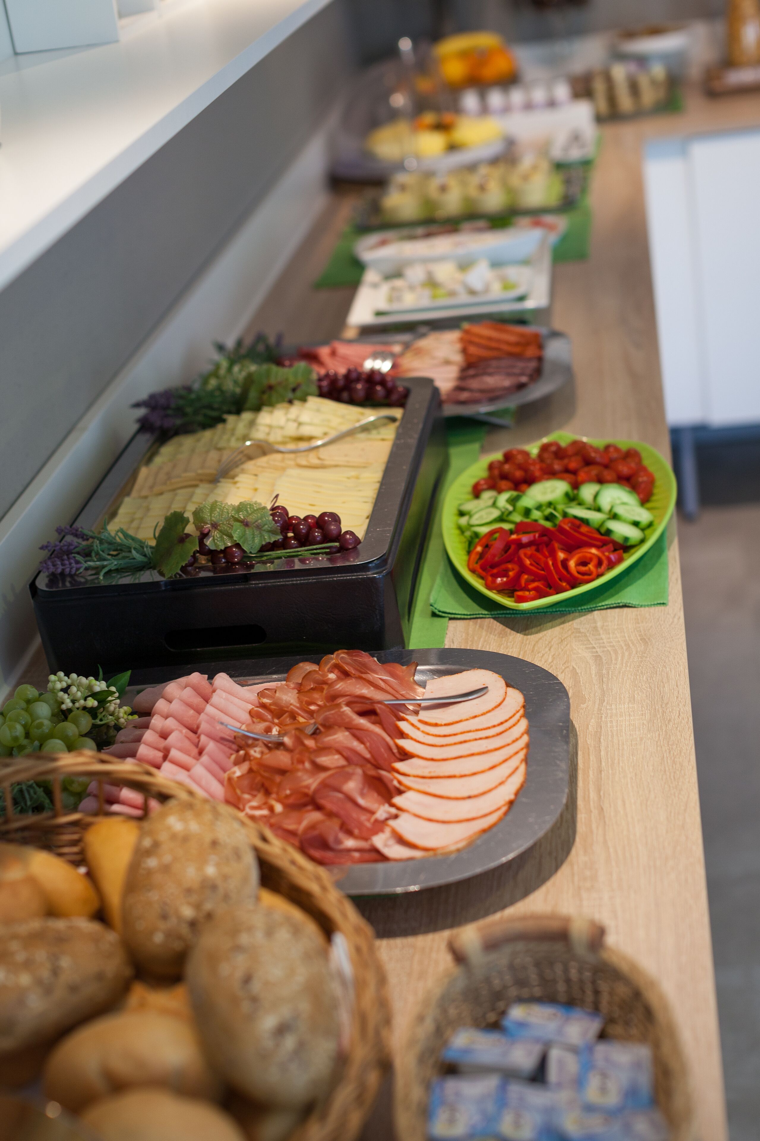 Un bufé con diversas opciones de comida, incluyendo carnes, quesos y verduras.
