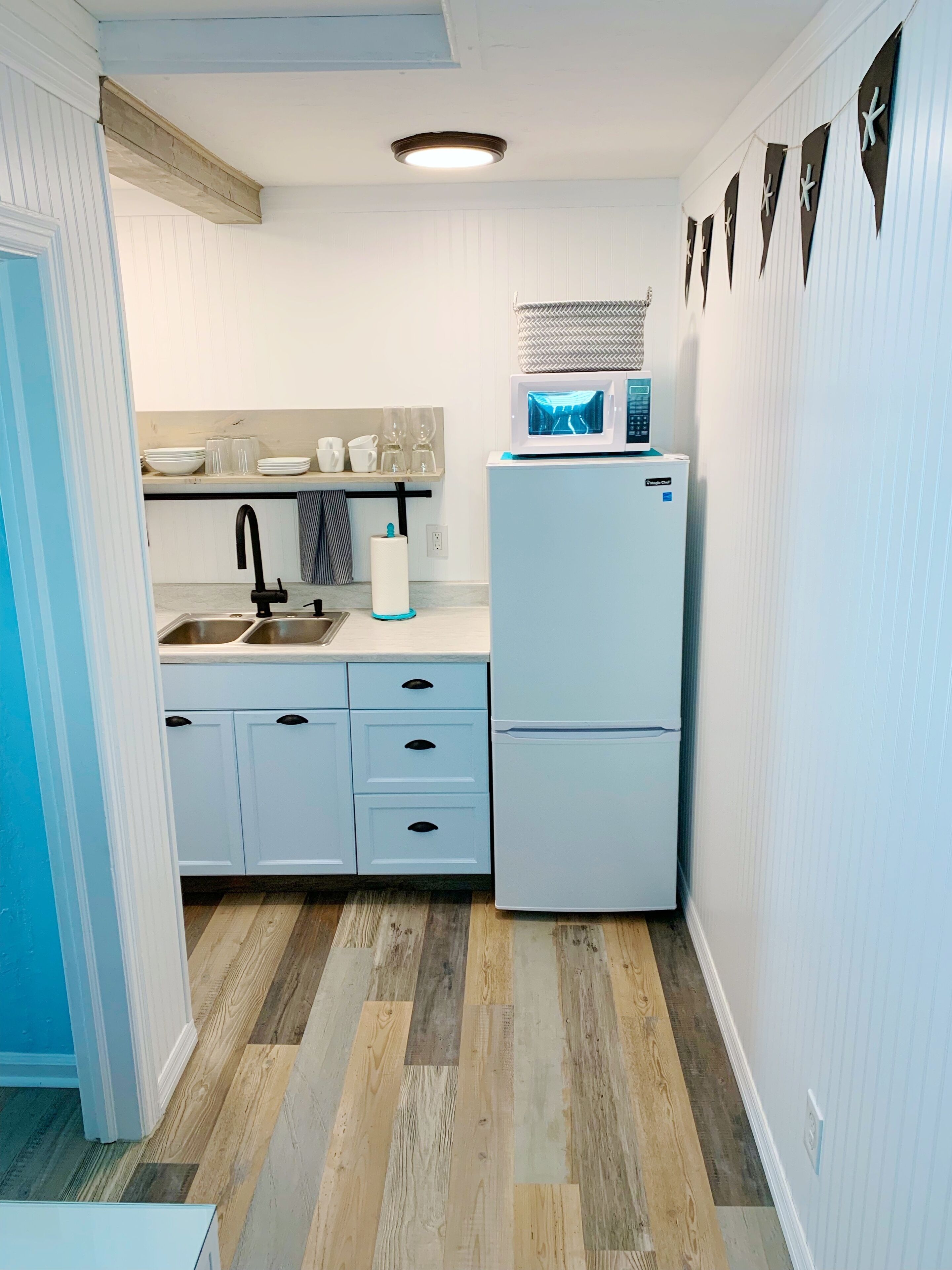 A compact kitchen with a sink, two drawers, a microwave, and a refrigerator.