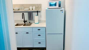 A compact kitchen with a sink, two drawers, a microwave, and a refrigerator.