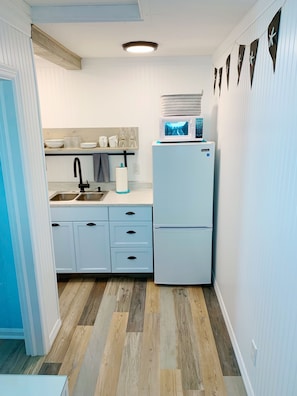A compact kitchen with a sink, two drawers, a microwave, and a refrigerator.