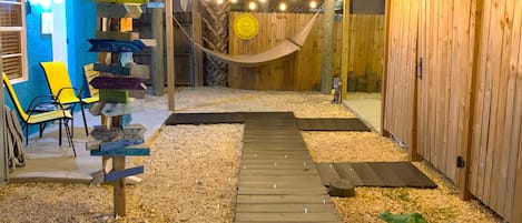 A wooden deck with a hammock, surrounded by wooden fences and a signpost with various destinations.