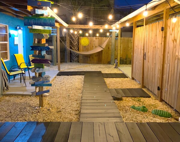 A wooden deck with a hammock, surrounded by wooden fences and a signpost with various destinations.