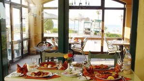 Un espace repas avec des tables dressées pour le repas, de grandes fenêtres et une vue sur l’extérieur.