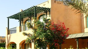 Un bâtiment agrémenté d’une pergola, de fenêtres en arc de cercle et d’une variété de plantes à fleurs.