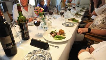 A dining table with plates of food, wine glasses, and a bottle of wine.