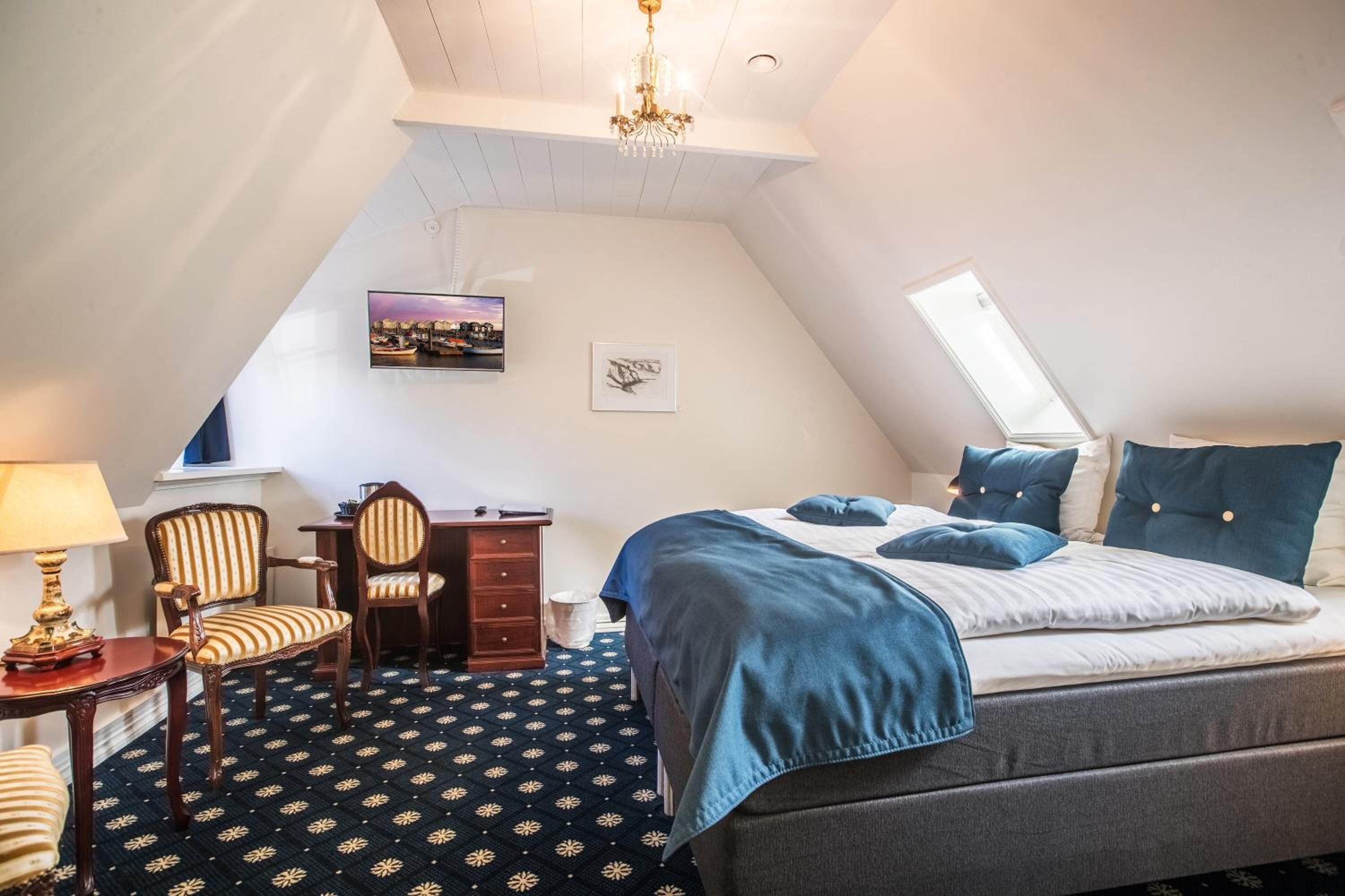 Un dormitorio con cama, escritorio, silla, lámpara y candelabro.