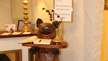 A wooden sculpture of a bear on a pedestal with a sign above it.