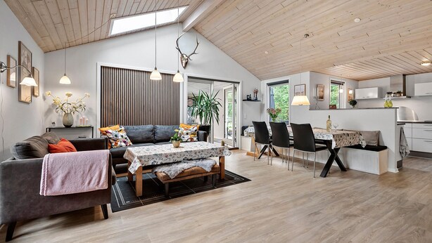 Een ruime woonkamer met een hoge plafond, een eettafel en een keuken.